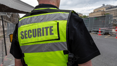 Gros plan d'un gilet jaune fluo avec le mot 'sécurité' écrit en français porté par un agent de sécurité privée surveillant un site sécurisé