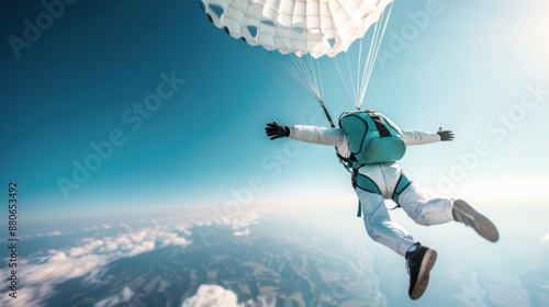 Skydiver gliding freely in the blue sky, adorned with a parachute and gear, showcasing the thrill and liberation of freefalling over an expansive terrain below.