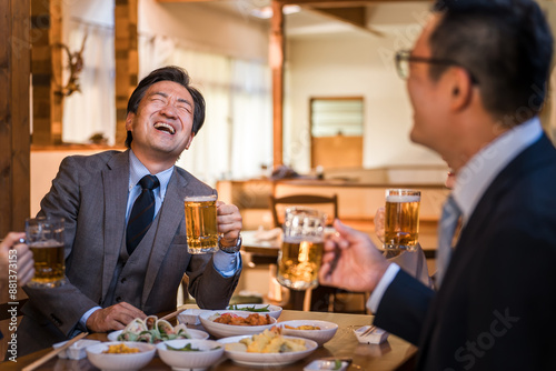 居酒屋で忘年会・新年会・飲み会・宴会で爆笑する中年のビジネスマン男性 