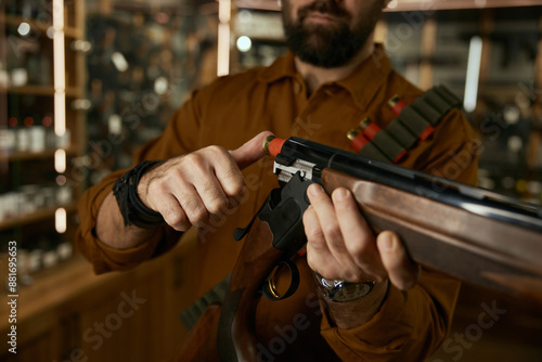 Man loading bullet into the rifle closeup at legal commercial weapon store for hunting hobby