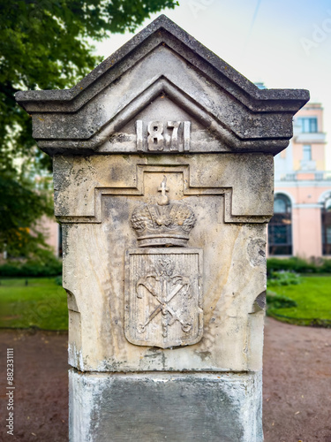 A detailed view of a historic stone monument featuring the inscription 1871 and an intricate emblem with a crown. This significant piece of architecture reflects the cultural heritage and history of