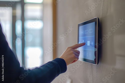 Woman using smart home automation system on wall mounted tablet