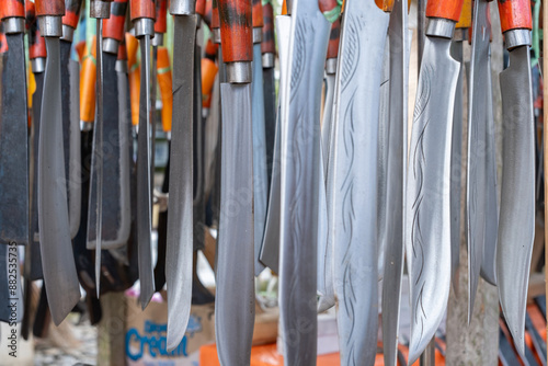 rows of machete swords with wooden handles in a traditional sharp weapons souvenir shop. Traditional sharp weapons background wallpaper concept