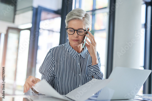 Woman, phone call and paperwork with laptop in office for investment, plan or report on client finance. Mature financial advisor, work and consulting with tech for foreign exchange, trading or update