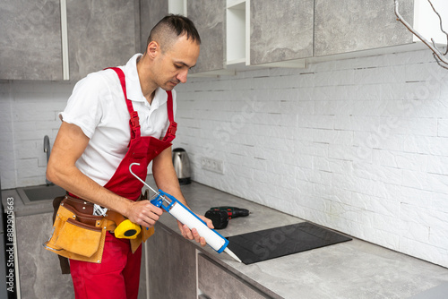 The carpenter places the induction hob in the space provided for the kitchen hob in the almost finished kitchen.