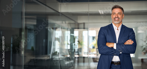 Handsome smiling confident hispanic senior man with crossed arms looking aside. Indian or latin successful mature middle age leader male businessman, business investor in office. Banner, copy space.