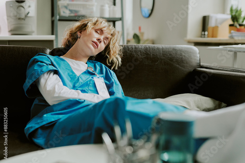 Tired young Caucasian nurse sleeping on comfort coach after her shift