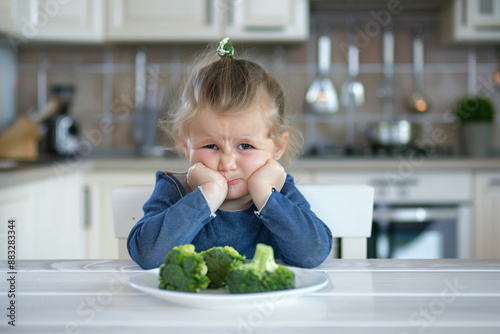 Little girl refusing to eat broccoli.