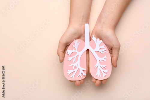 Female hands with paper lungs on beige background