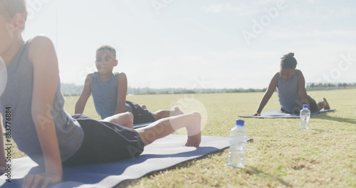 Image of light spots over happy diverse schoolboys stretching in outdoor yoga class