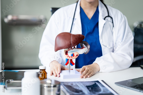 A young female nurse works at a desk, discussing liver-related conditions with a grey-haired Asian mature woman, including liver disease, hepatitis, cirrhosis, and liver cancer.