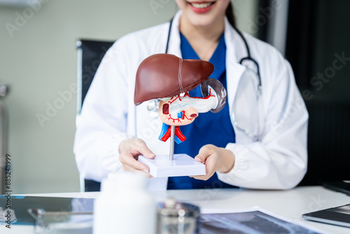 A young female nurse works at a desk, discussing liver-related conditions with a grey-haired Asian mature woman, including liver disease, hepatitis, cirrhosis, and liver cancer.