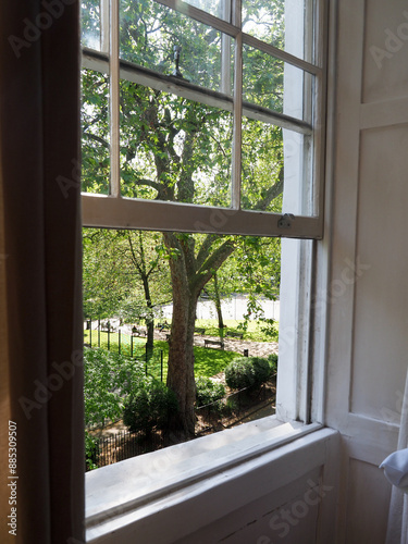 An open sash window looking out onto a lovely park in the summer