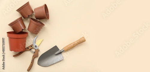 Pots, pruner and shovel on beige background with space for text