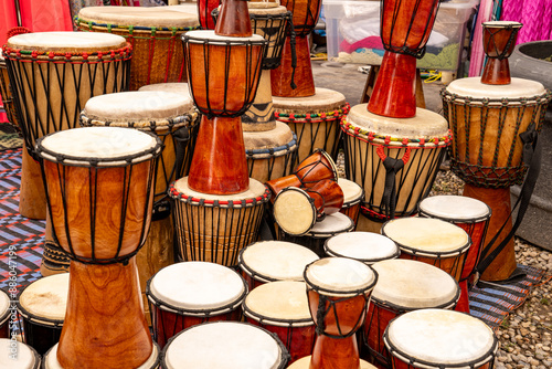 Traditional handmade djembe drums displayed at a market. The single-headed goblet drum comes from West Africa. Its body is made from a hollowed-out tree trunk.