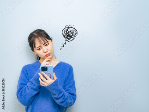 スマホを見ながら悩む女性