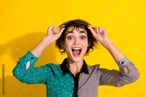 Photo of excited lovely woman wear stylish clothes hands hold glasses isolated on yellow color background