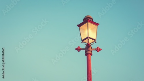 Vintage gaslight street lamp on tall red wooden pole against clear summer sky