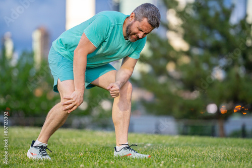 Middle aged Man are knee pain. Arthritis and tendon problems. A man touching knee at pain point. Running, injury and old man with knee pain outdoor. Knee pain during workout.