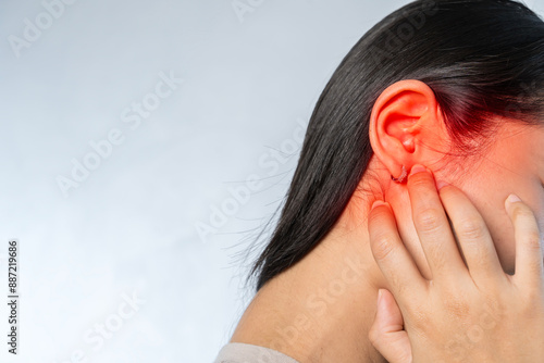 Young woman suffering from ear pain and tinnitus. Cause of earache includes otitis, earwax buildup.