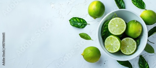 White background with fresh limes in a bowl complete with copy space image