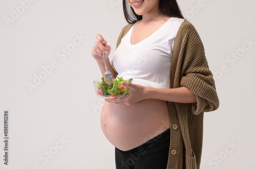 Portrait of Beautiful pregnant woman eating salad over white background studio, health and maternity concept.