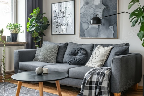Modern Scandinavian living room with gray sofa pillows plants wooden commode black table lamp and abstract paintings Stylish home decor