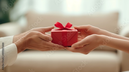 Person giving gift box with red ribbon to another person.