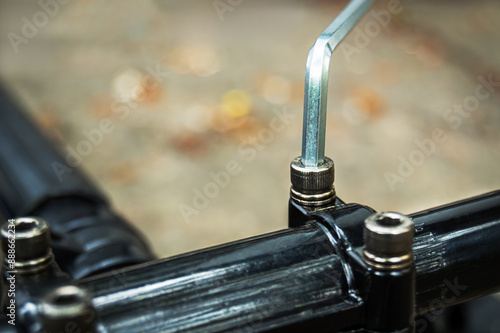 Close-up of a bolt being tightened with a crosshead on a mechanical fastener, against a blurred background. Work, mechanic