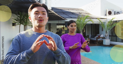 Image of spots of light over diverse couple exercising by swimming pool at home