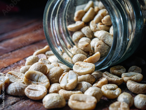 Green coffee beans poured out of a glass jar, Close-up of green raw coffee bean, unroasted coffee bean