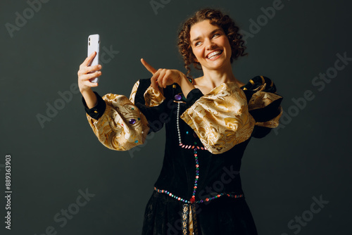 Portrait of a young aristocratic woman doing photo selfie with mobile phone and dressed in a medieval dress