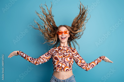 Portrait of nice young girl arms throw flying hair wear top isolated on blue color background