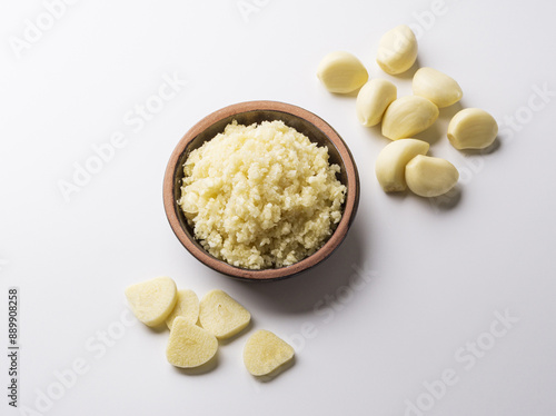 Top angle view of chopped garlic on jar with peeled garlic seeds and cut ones on white floor, South Korea 