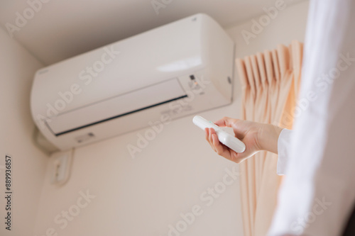 A woman turning on the air conditioner. Person turning off the air conditioner. エアコンのスイッチをつける女性。エアコンのスイッチを消す人。