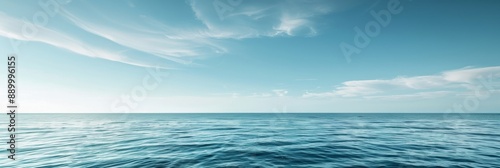 The vast expanse of the ocean stretches out before a clear blue sky dotted with wispy white clouds