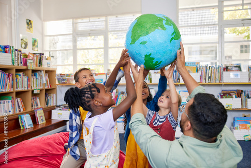 School children with teacher holding earth model in a library