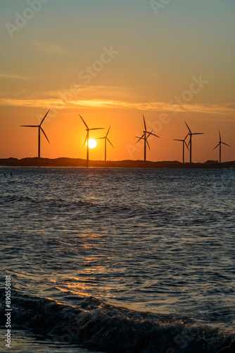 Wind energy. Sun setting behind wind energy farm on Icarai de Amontada beach, CE, Brazil on July 1, 2024.