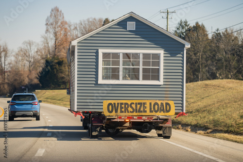 Oversize load home. Manufactured house transported on the highway. Mobile Home oversize load on the road. Transporting portable homes. Oversized cargo. Truck Oversized transport for mobile home.