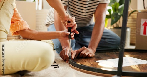 Hands, screwdriver and table with couple in living room of home for DIY, renovation or repairs. Building, moving in and tool with people on floor of apartment for construction of furniture together