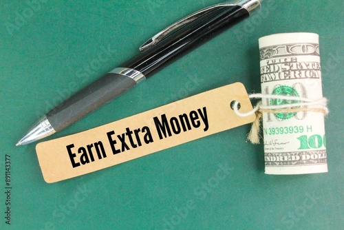 paper money, pens and paper tags with the words earn extra money. the concept of finding income or profit