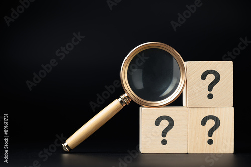 Magnifying glass and stack of question mark wood cubes, analyze the questions, FAQs, and questions that need the answer 