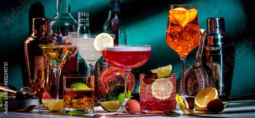 Cocktails. Strong drinks and aperitifs, bar tools, bottles on dark green background, hard light