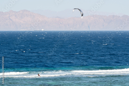 A person kiteboarding in the Red Sea on sunny spring day. Dahab, Egypt.