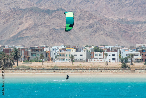 A person kiteboarding in Lagoon on the background of Dahab town on sunny day. Egypt.