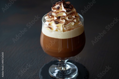 Elegant glass of irish coffee topped with whipped cream and chocolate shavings on a dark backdrop