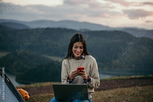 Beautiful woman enjoying camping alone and using a laptop and phone