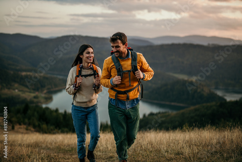 Shot of a couple going for a hike up the mountain, lake in the background