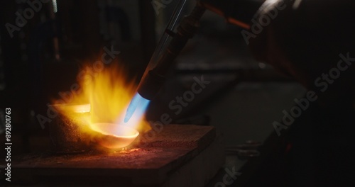 Goldsmith melting gold in crucible with blow torch