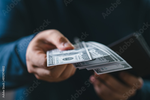 Close-up of a person handing over US dollar bills. Concept of payment, transaction, finance, banking, and cash handling.